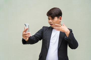 portrait of a young cute gay businessman looking surprised while using phone