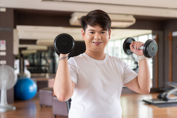 Happy young gay man working out with dumbbells