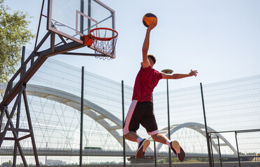 Sportmen playing game of basketball at outdoor court