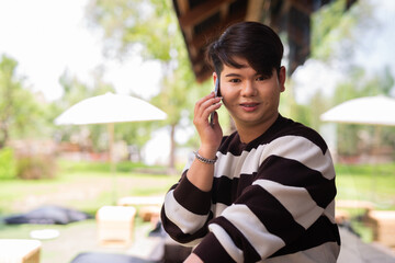Portrait of a young gay man sitting outside of cafe restaurant during summer