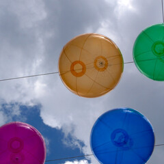 Fototapeta premium colorful balloons hanging in the sky in front of bright summer rain clouds