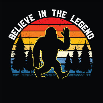 Retro-style Bigfoot graphic featuring a silhouette of Sasquatch waving in front of a sunset-colored striped background with pine trees and the phrase "Believe in the Legend." Perfect for fans of crypt