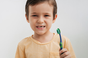 Portrait of a smiling little boy without a baby tooth with a toothbrush, close-up. Oral care in children.