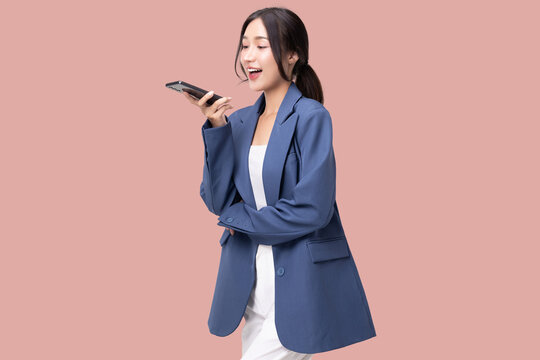 Portrait of happy young business woman talking with AI on smartphone isolated on pink background.