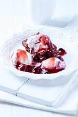 Strawberry ice cream with chocolate and cherry syrup on chocolate brownie. Selective focus.