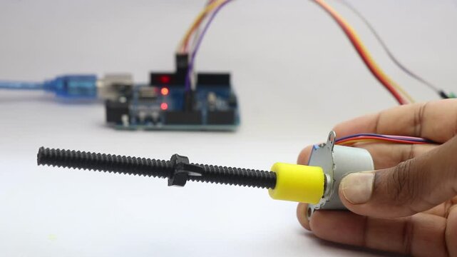 Stepper motor with its shaft connected to a 3d printed part is being rotated and it is controlled by micro controller on background