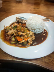 Delicious Asian stir-fried chicken with vegetables in savory brown sauce served with steamed white rice – traditional homemade meal on wooden table, perfect for food photography, culinary blog, and re