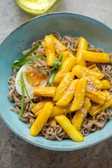 Turquoise bowl with korean rabokki or a combination of tteokbokki and ramen noodles, vertical shot, middle close-up