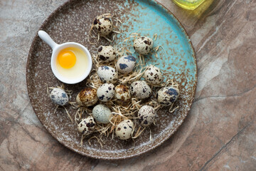 Brown plate with raw fresh quail eggs, horizontal shot on a brown granite background, view from above
