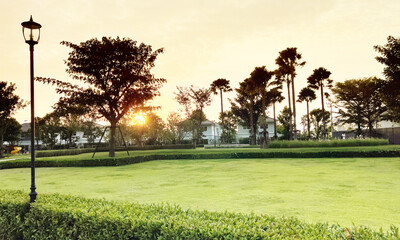 Outdoor landscape image of small public park in peaceful suburb area of Bangkok with beautiful sunset and silhouette trees in tropical summer season background.