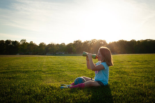 Young girl taking water break during soccer practicce sunny day