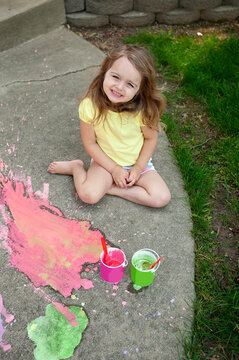 Happy little girl blonde curls painting with colorful sidewalk c