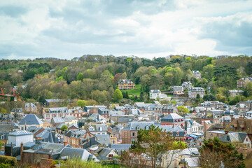 Cityscape view of a quaint town surrounded by greenery on a cloudy day in France