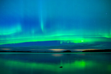 Northern lights dancing over lake in Farnebofjarden national park in north of Sweden