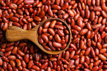 Red kidney beans on a wooden cup spoon with red beans background. Food ingredients. Top view