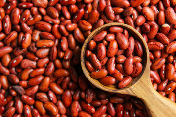 Red kidney beans on a wooden cup spoon with red beans background. Food ingredients. Top view