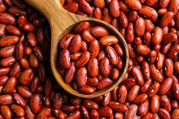 Red kidney beans on a wooden cup spoon with red beans background. Food ingredients. Top view
