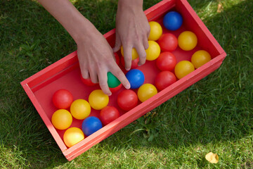 People Playing with Colorful Plastic Balls in a Wooden Box