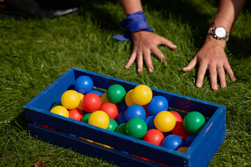 People Playing with Colorful Plastic Balls in a Wooden Box