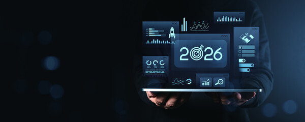 Businessman holding tablet with futuristic 2026 analytics and data dashboard.