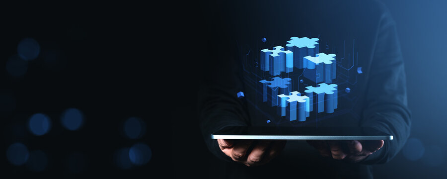 Digital blue puzzle pieces hovering above tablet in dark tech environment.