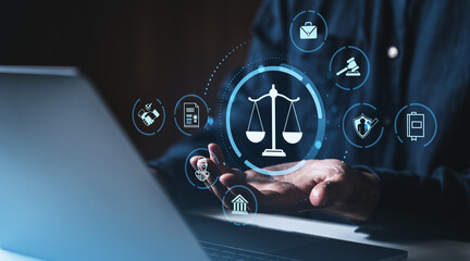 Digital justice icons floating above hand near laptop in dark office scene.