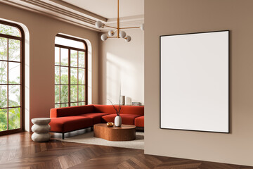 Modern interior with blank poster on beige wall in stylish living room featuring red sofa, wooden accents, and large windows with natural view. 3D Rendering