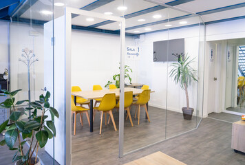 Modern meeting room with yellow chairs and glass walls promoting collaboration and transparency