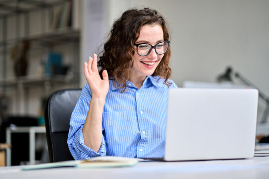 Busy happy business woman hr manager having remote online work hybrid meeting or job interview. Young female employee waving hand looking at laptop during virtual video conference call in office.