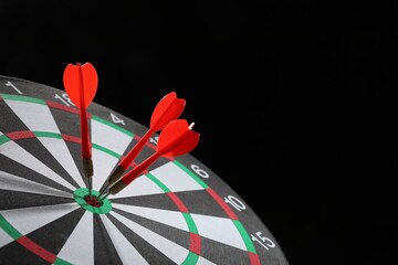 Targeting. Dart board with arrows on black background, closeup. Space for text