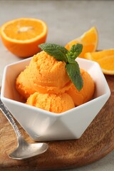Balls of tasty orange sorbet, fresh fruit, mint and spoon on light table, closeup