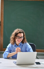 Young happy business woman employee or teacher feeling pleased and excited looking at laptop reading good news online about career growth, satisfied with great result sitting at work desk. Vertical