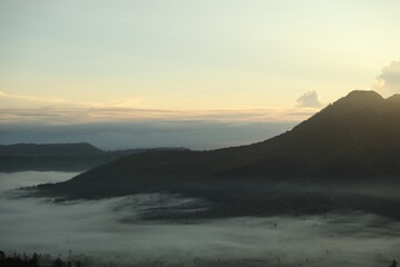 Picturesque view of mountains covered with fog on sunset