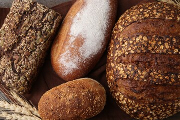 Freshly baked loaves of bread and spikes on wooden table, flat lay