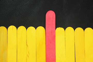 A row of yellow sticks and a red stick. unique concept.  standing out from the crowd, leadership,...