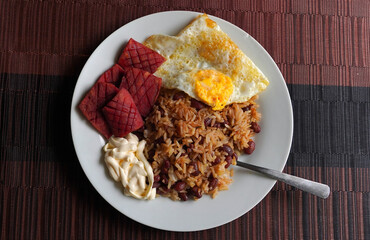 Gallo pinto, a typical Costa Rican dish with rice, red beans, sausage, cream, and a fried egg, and...