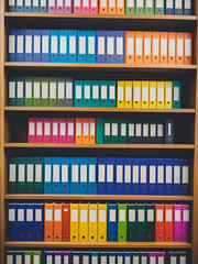 A bookshelf filled with variously colored binders, perfect for organizing and categorizing documents