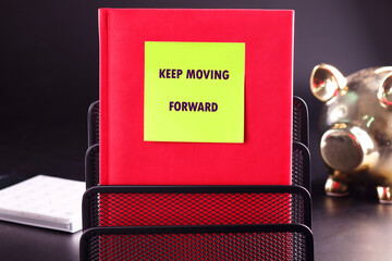Business, motivation and keep moving forward concept. KEEP MOVING FORWARD written on a yellow sticker stuck on a red business notebook