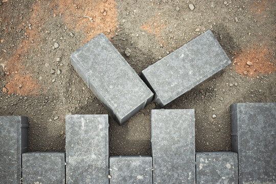 Construction workers arranging gray bricks on a construction site during daylight hours