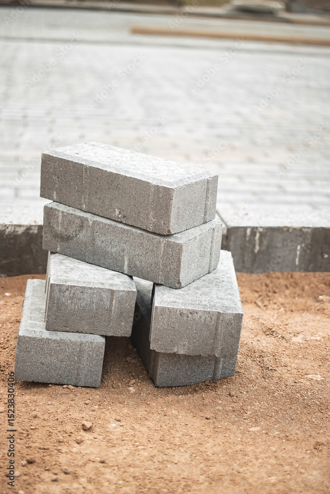 Poster stacked gray concrete blocks on a construction site with a paved area in the background