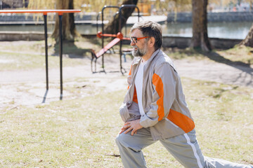 Senior man stretching legs in a calisthenics park