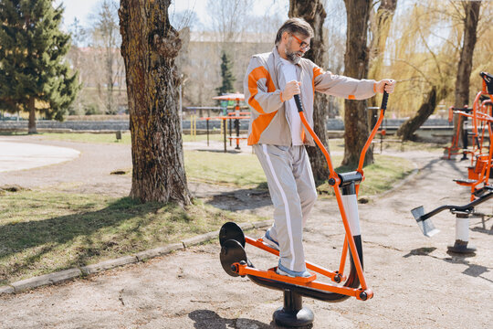 Senior man exercising on elliptical trainer in outdoor gym