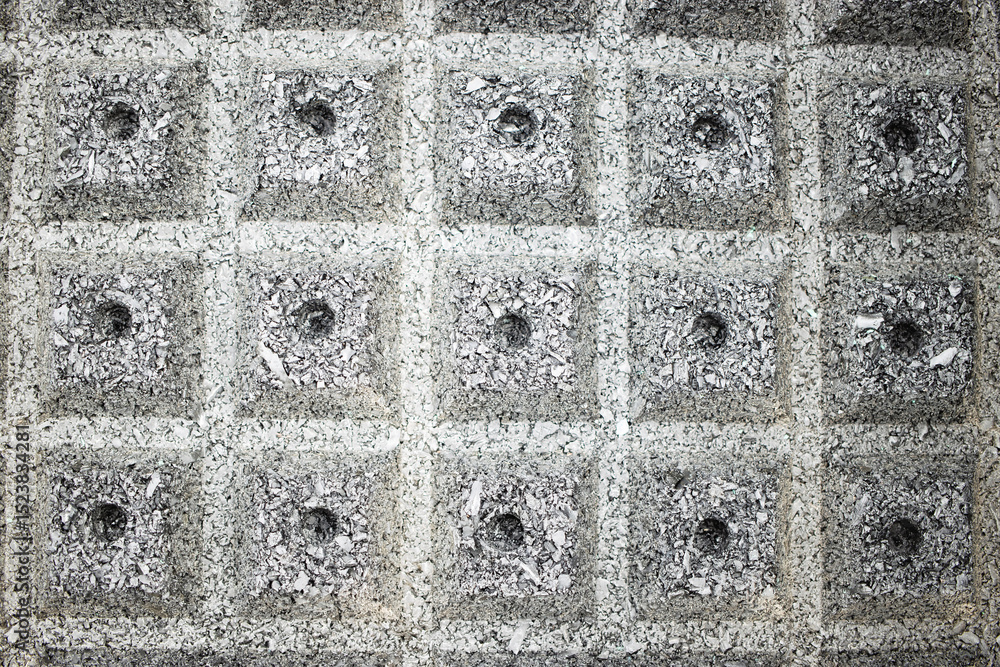Poster texture of concrete blocks arranged in a grid pattern with circular impressions on a construction si