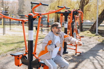 Senior man having chest pain while exercising on outdoor gym equipment