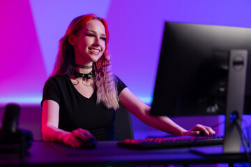 Smiling gamer enthusiast working at a computer in a colorful gaming setup