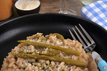 Risotto aux asperges vertes fait maison avec une fourchette servi dans une assiette en gros plan