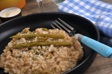 Risotto aux asperges vertes fait maison avec une fourchette servi dans une assiette en gros plan