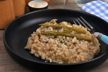 Risotto aux asperges vertes fait maison avec une fourchette servi dans une assiette en gros plan
