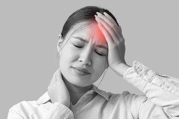 Young Asian woman suffering from headache on beige background. Brain Injury Awareness Month