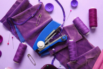 Manual sewing machine with different supplies on lilac background